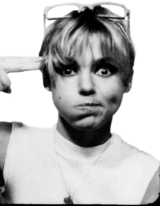 photo of Edie Sedgwick holding her index and middle finger to her head